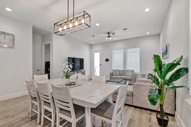 dining space with light hardwood / wood-style floors and ceiling fan with notable chandelier