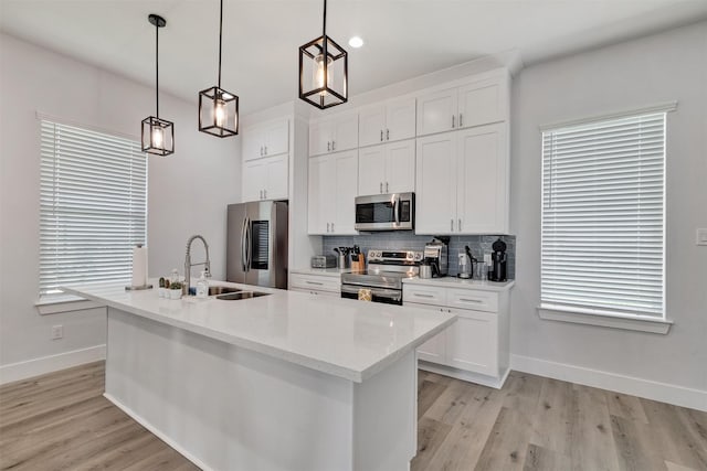 kitchen featuring a kitchen island with sink, hanging light fixtures, and stainless steel appliances