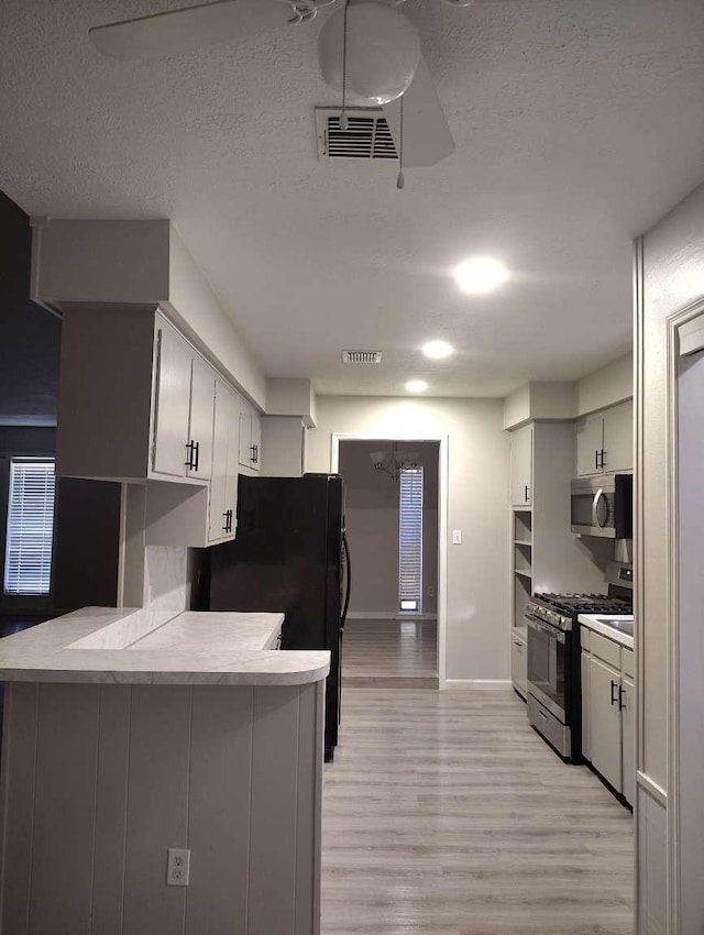 kitchen featuring kitchen peninsula, a textured ceiling, stainless steel appliances, and light hardwood / wood-style flooring