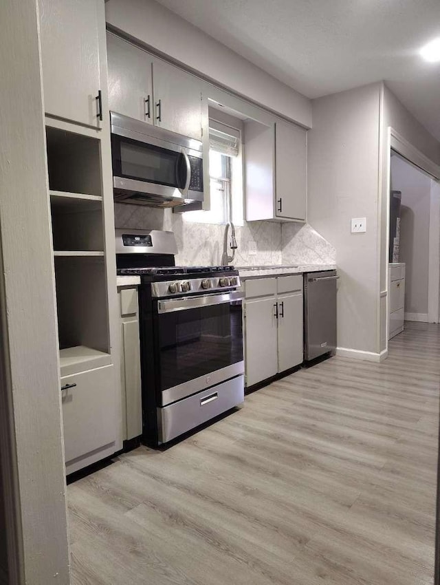 kitchen featuring decorative backsplash, light wood-type flooring, and stainless steel appliances