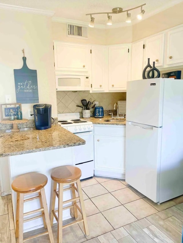 kitchen with light stone countertops, white appliances, crown molding, sink, and white cabinetry