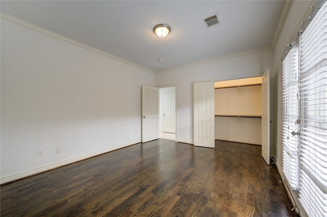 unfurnished bedroom with dark hardwood / wood-style floors, a walk in closet, ornamental molding, and a closet