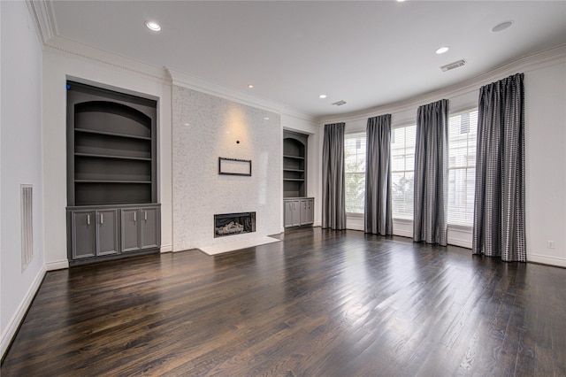 unfurnished living room with built in shelves, a large fireplace, dark hardwood / wood-style flooring, and crown molding