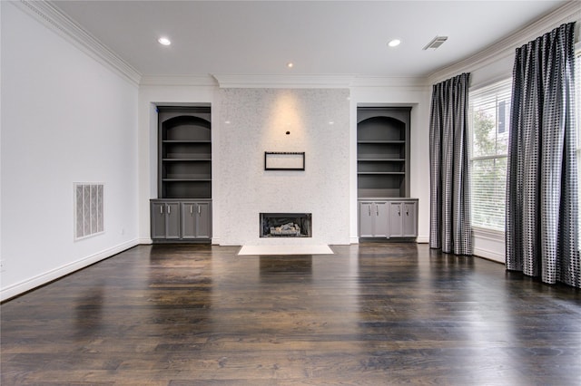 unfurnished living room with built in shelves, a large fireplace, dark hardwood / wood-style flooring, and crown molding