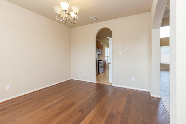 unfurnished room with hardwood / wood-style floors and a chandelier