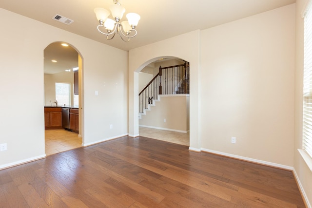 spare room with light wood-type flooring, sink, and an inviting chandelier