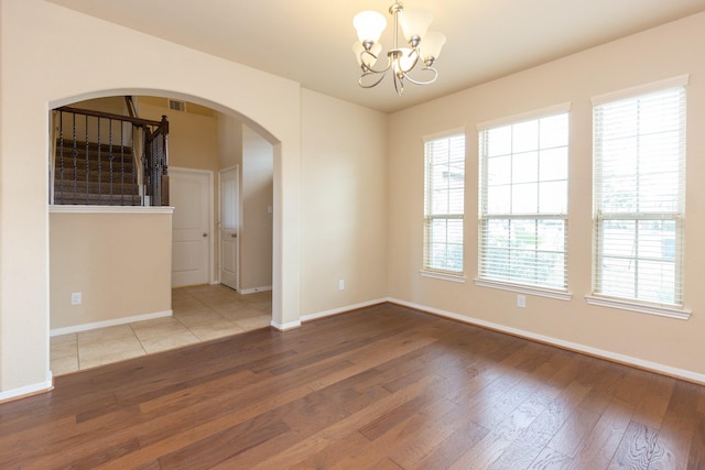 empty room with hardwood / wood-style floors and a chandelier