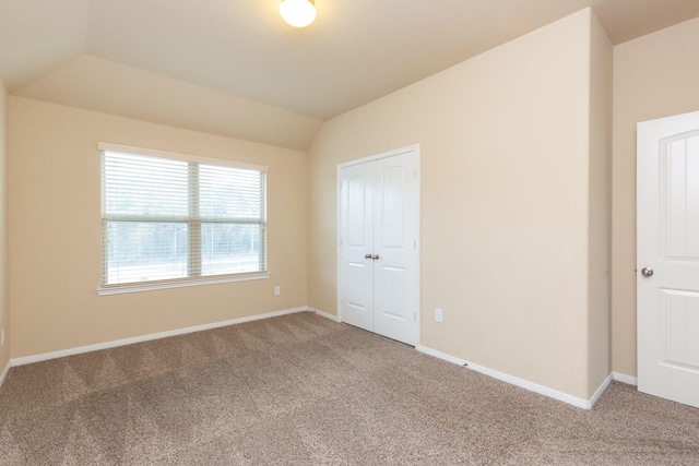 unfurnished bedroom featuring carpet floors, vaulted ceiling, and a closet