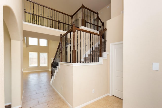 stairs with a towering ceiling and tile patterned floors