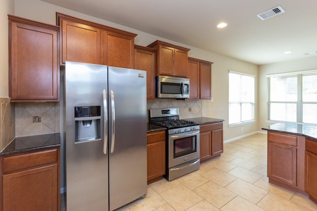 kitchen featuring dark stone countertops, light tile patterned floors, appliances with stainless steel finishes, and tasteful backsplash