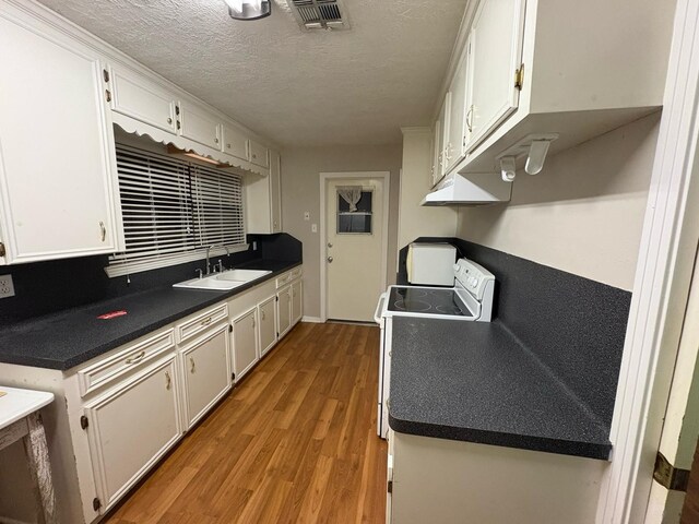 kitchen featuring sink, white cabinetry, a textured ceiling, hardwood / wood-style flooring, and stove