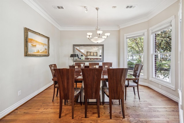 dining area with hardwood / wood-style flooring, ornamental molding, and a chandelier