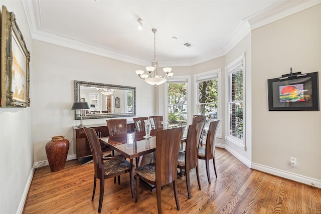 dining room with light hardwood / wood-style floors, an inviting chandelier, and crown molding