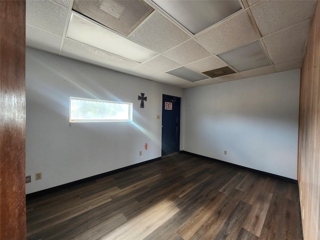 unfurnished room with a paneled ceiling and dark hardwood / wood-style floors