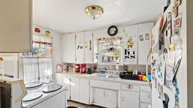 kitchen with white cabinetry, sink, white fridge, and range