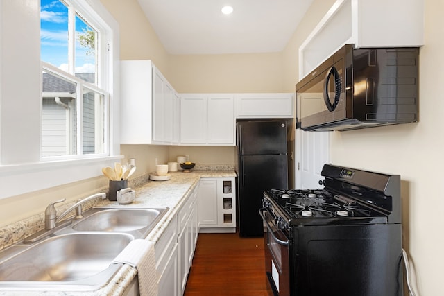 kitchen with light stone counters, dark wood-type flooring, sink, black appliances, and white cabinets