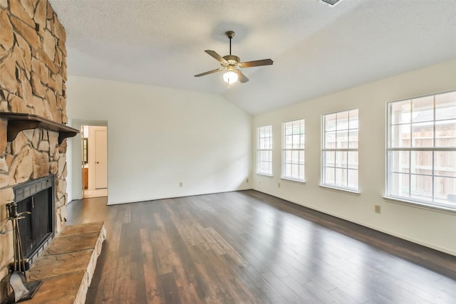 unfurnished living room with a textured ceiling, ceiling fan, dark wood-type flooring, a stone fireplace, and lofted ceiling