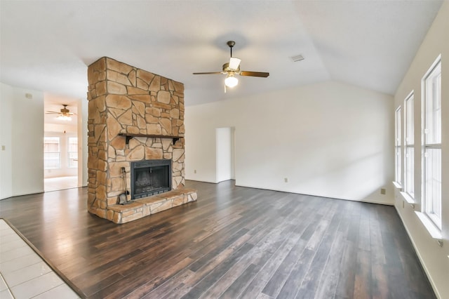 unfurnished living room with ceiling fan, a stone fireplace, dark wood-type flooring, and vaulted ceiling