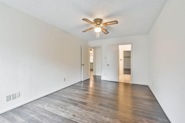 empty room with ceiling fan, dark hardwood / wood-style flooring, and a textured ceiling