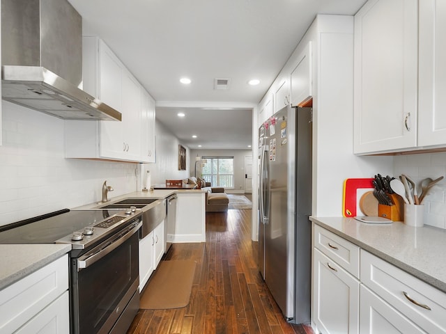 kitchen featuring white cabinets, dark hardwood / wood-style floors, wall chimney range hood, and appliances with stainless steel finishes