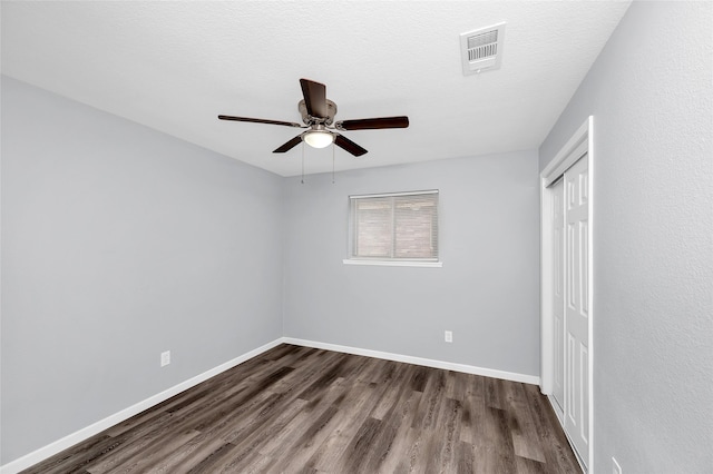 unfurnished bedroom with ceiling fan, dark hardwood / wood-style flooring, and a textured ceiling