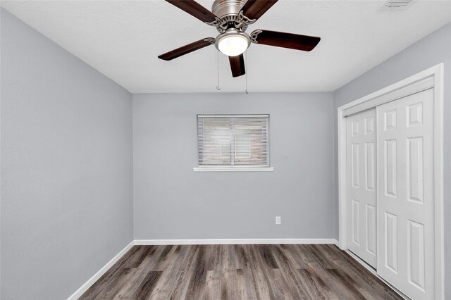 unfurnished bedroom with ceiling fan, dark hardwood / wood-style floors, a textured ceiling, and a closet