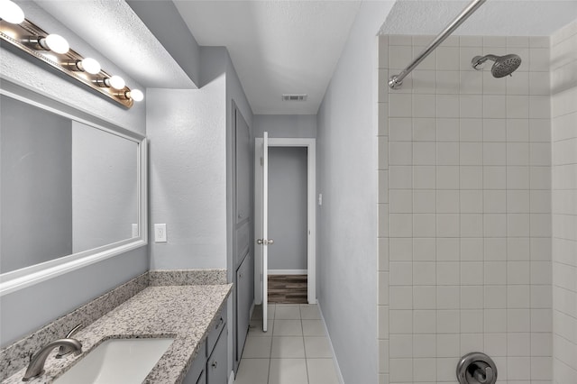 bathroom featuring tile patterned floors, vanity, a textured ceiling, and tiled shower / bath