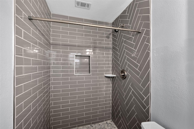 bathroom featuring a textured ceiling and tiled shower