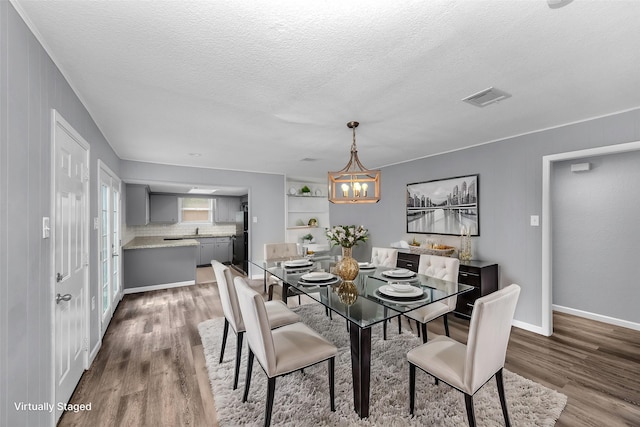 dining room featuring a textured ceiling, a notable chandelier, wood walls, and dark wood-type flooring