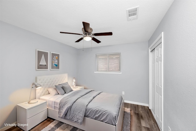 bedroom with ceiling fan, dark hardwood / wood-style flooring, and a textured ceiling