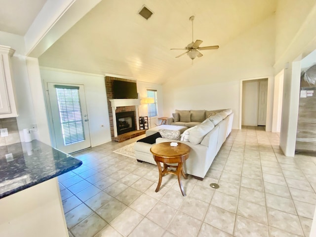 living room featuring high vaulted ceiling, a brick fireplace, ceiling fan, and light tile patterned flooring