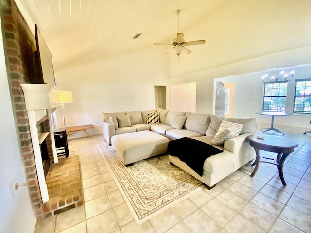 tiled living room featuring ceiling fan with notable chandelier, high vaulted ceiling, and a brick fireplace