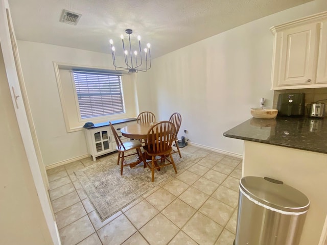 dining space with a chandelier, light tile patterned floors, and a textured ceiling