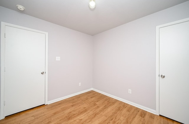 spare room featuring baseboards and light wood-style floors