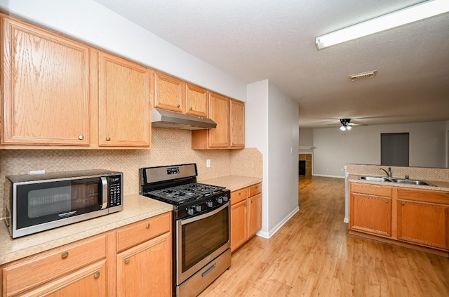 kitchen with light wood finished floors, visible vents, stainless steel appliances, under cabinet range hood, and a sink