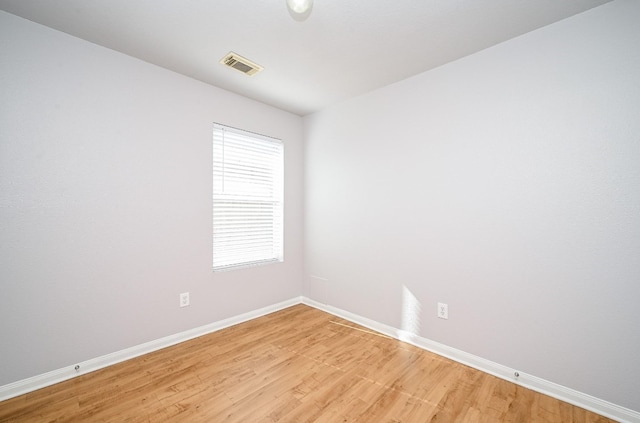 empty room featuring light wood-style floors, visible vents, and baseboards