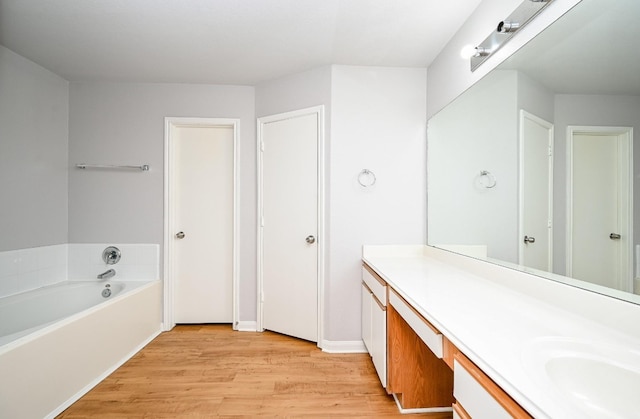 bathroom with a bath, wood finished floors, and vanity