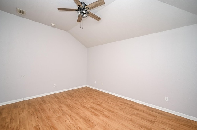 empty room featuring lofted ceiling, light wood-type flooring, baseboards, and visible vents