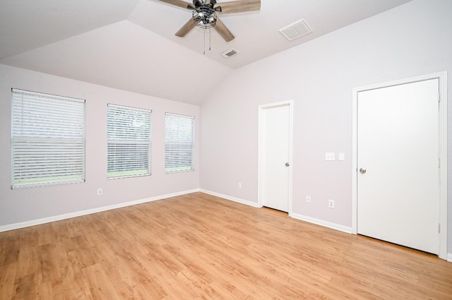 unfurnished room with light wood-type flooring, visible vents, vaulted ceiling, and baseboards