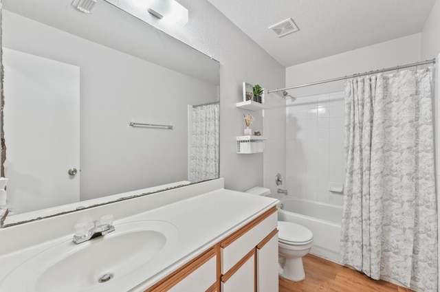 full bathroom with toilet, vanity, hardwood / wood-style flooring, a textured ceiling, and shower / tub combo with curtain