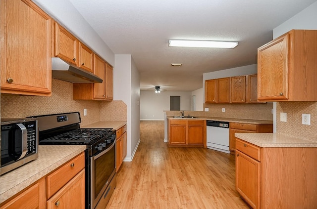 kitchen with sink, ceiling fan, light hardwood / wood-style floors, backsplash, and appliances with stainless steel finishes