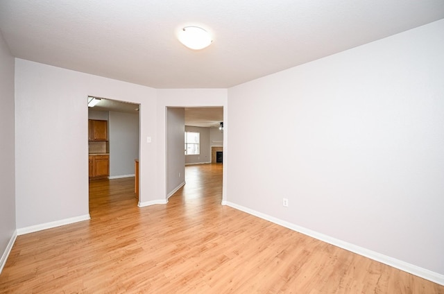 empty room featuring light wood finished floors, baseboards, and a tile fireplace