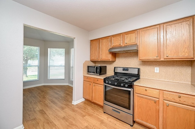 kitchen with stainless steel appliances, light countertops, under cabinet range hood, and decorative backsplash