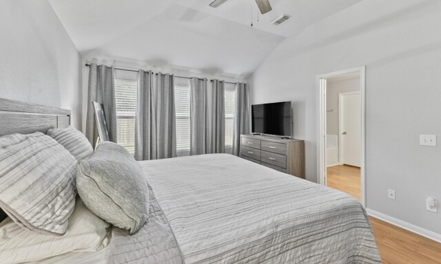 bedroom featuring ceiling fan, light hardwood / wood-style flooring, vaulted ceiling, and multiple windows