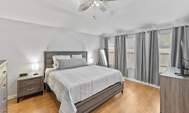 bedroom with light wood-type flooring, baseboards, vaulted ceiling, and a ceiling fan