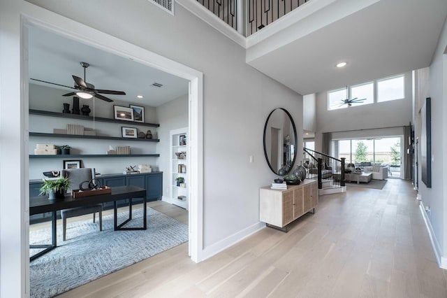 hallway with a high ceiling and light hardwood / wood-style floors