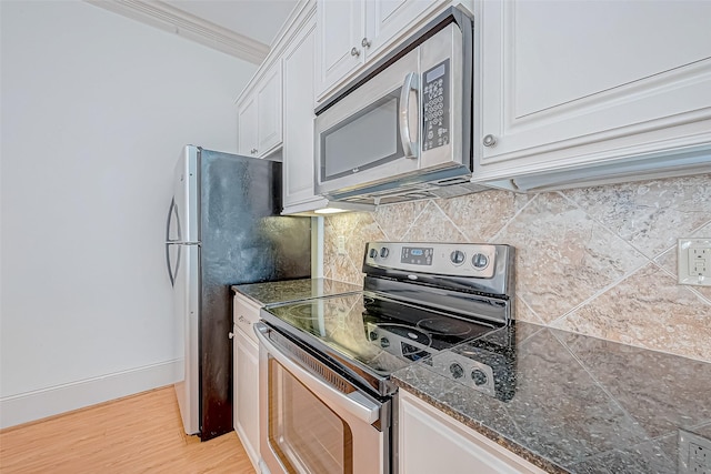 kitchen with white cabinets, ornamental molding, appliances with stainless steel finishes, tasteful backsplash, and light hardwood / wood-style floors