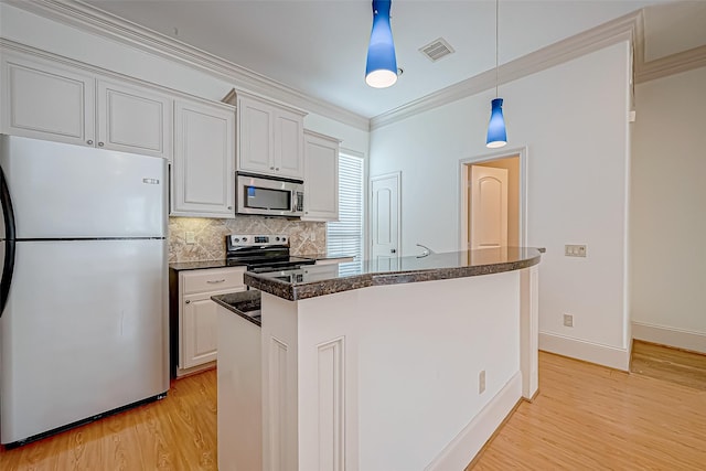 kitchen featuring hanging light fixtures, crown molding, light hardwood / wood-style floors, white cabinets, and appliances with stainless steel finishes