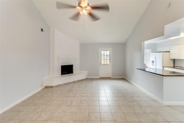 unfurnished living room featuring ceiling fan, light tile patterned flooring, a fireplace, and vaulted ceiling