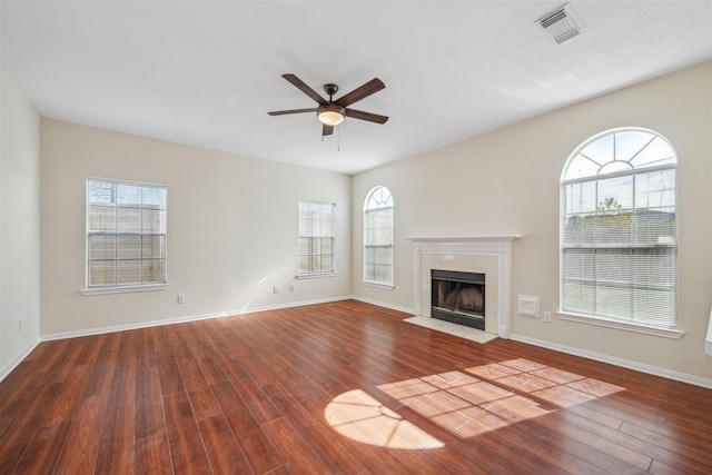 unfurnished living room with ceiling fan, dark wood-type flooring, and a wealth of natural light